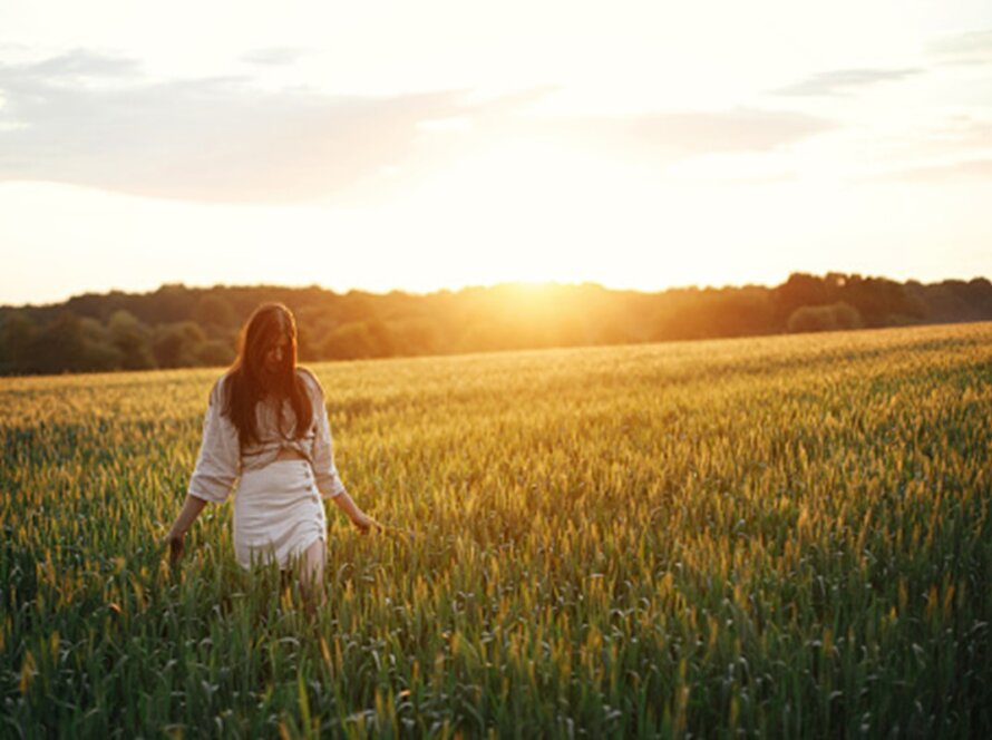 Mujer caminando tranquila en un campo de trigo al atardecer simbolizando la paz interior y la libertad.