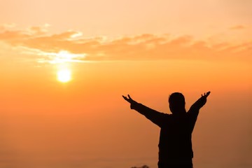 Persona adorando a Dios al amanecer como símbolo de confianza, esperanza y victoria sobre el temor.