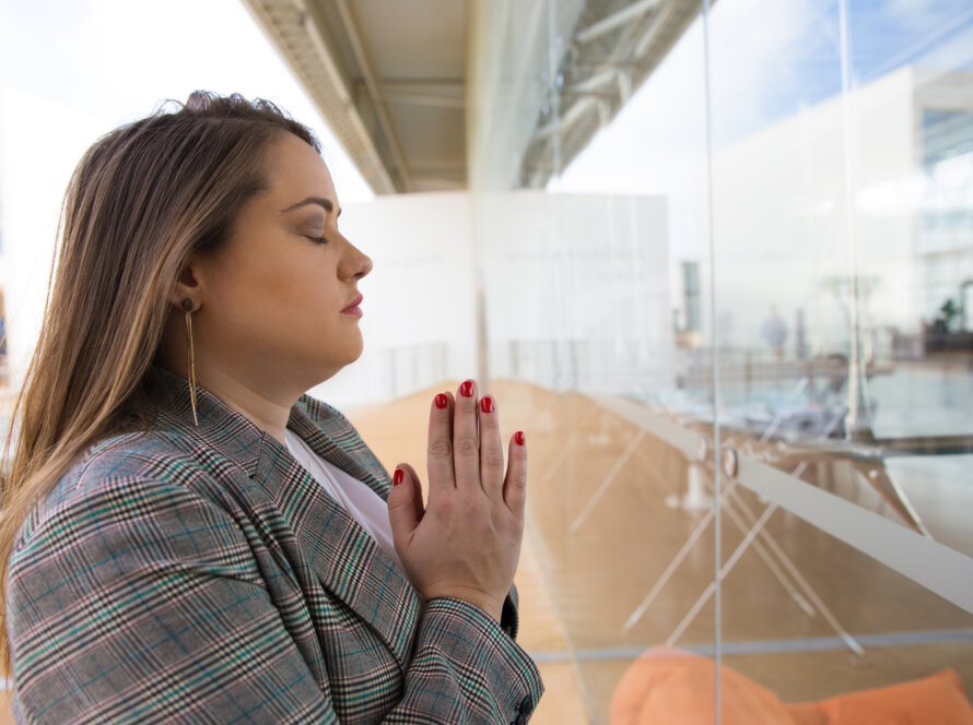 Profesional cristiana en un entorno laboral orando con fe por favor y gracia en su empleo
